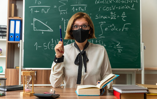 teacher in front of chalkboard with face mask