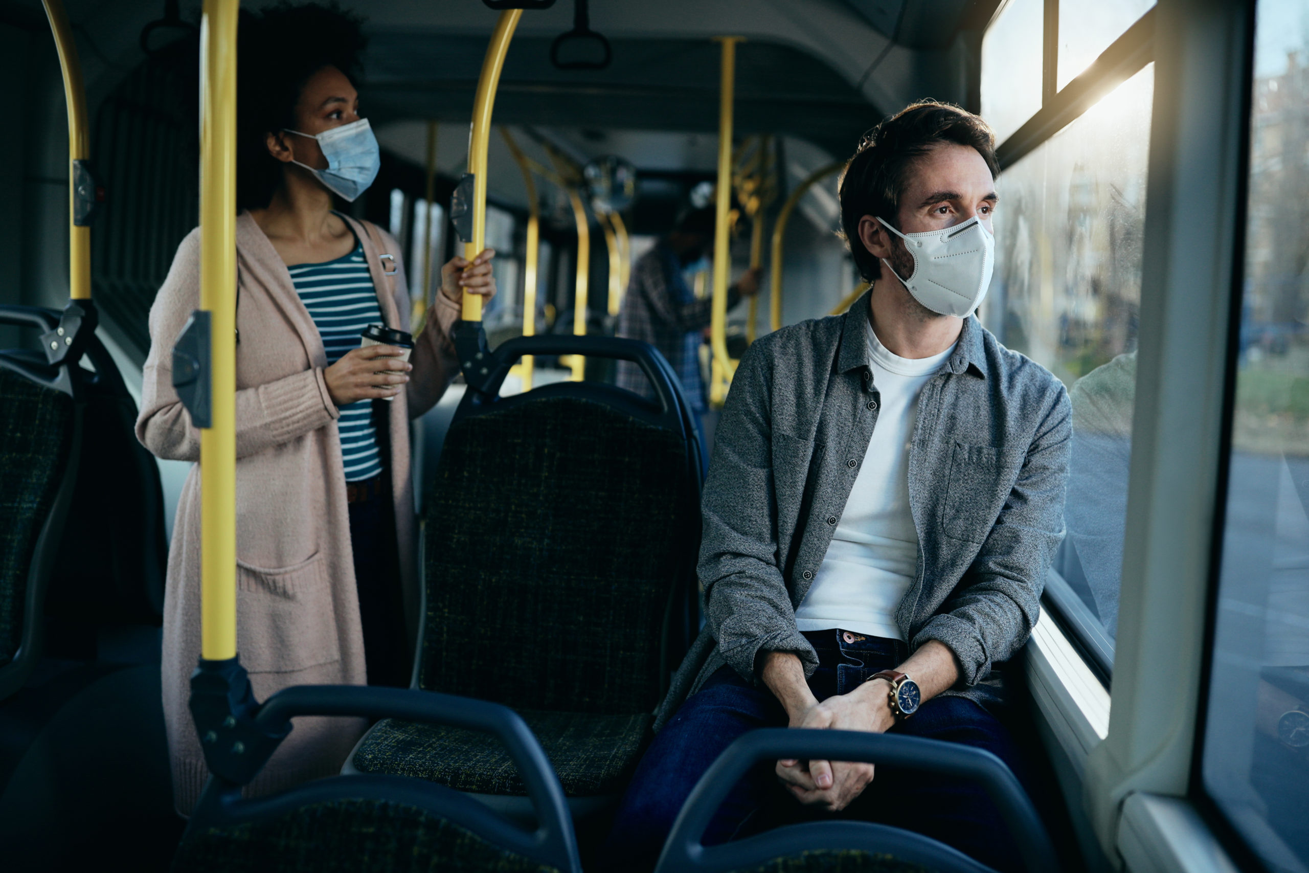 Man with protective face mask thinking of something while traveling by public transport and looking through the window.